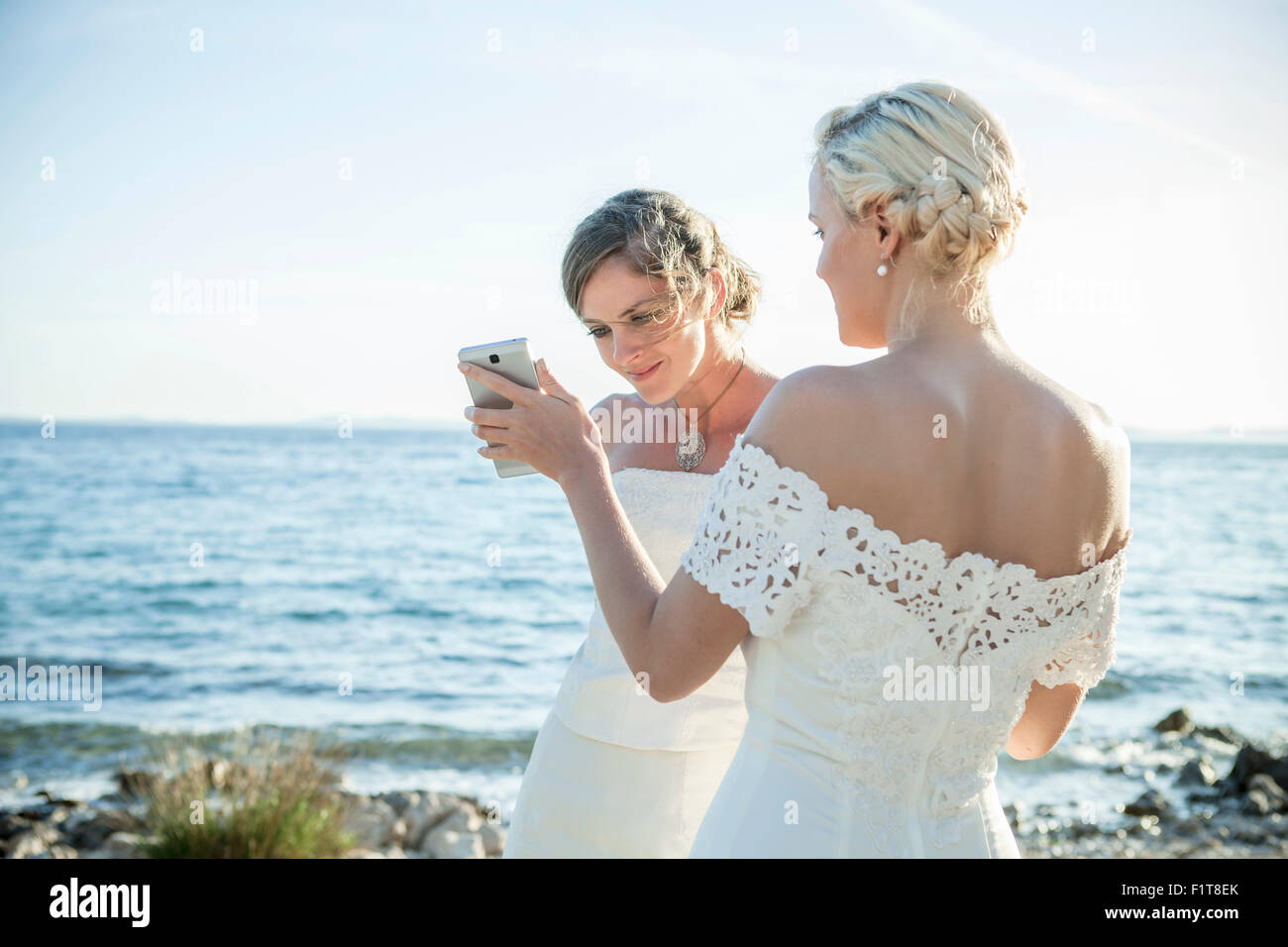 Sposa e damigella di messaggistica di testo all'aperto Foto Stock