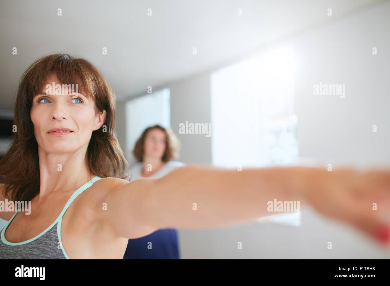 Fiducioso allenatore femmina facendo yoga allenamento in palestra. Le donne a praticare yoga in classe. Foto Stock