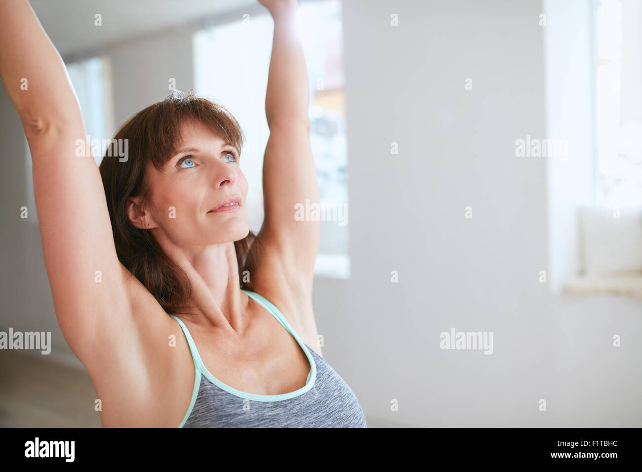 Immagine ravvicinata di donna matura la pratica dello yoga con le braccia sollevate e guardando verso l'alto in palestra. Femmina Fitness in posa del Guerriero I Foto Stock