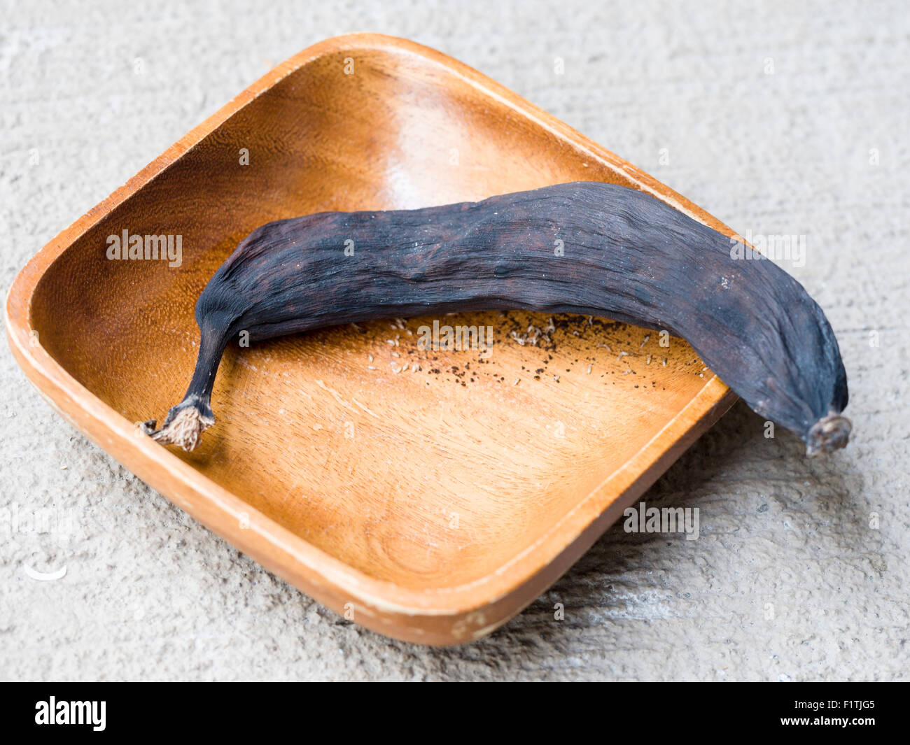 Marciume nero Banana in una ciotola di legno. Una banana lasciata maturare troppo lungo diventa nero, secco e attrae vermi. Foto Stock