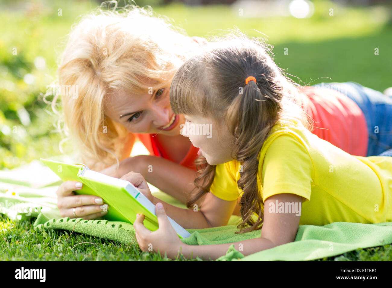 Madre e figlia e la lettura di un libro al parco Foto Stock