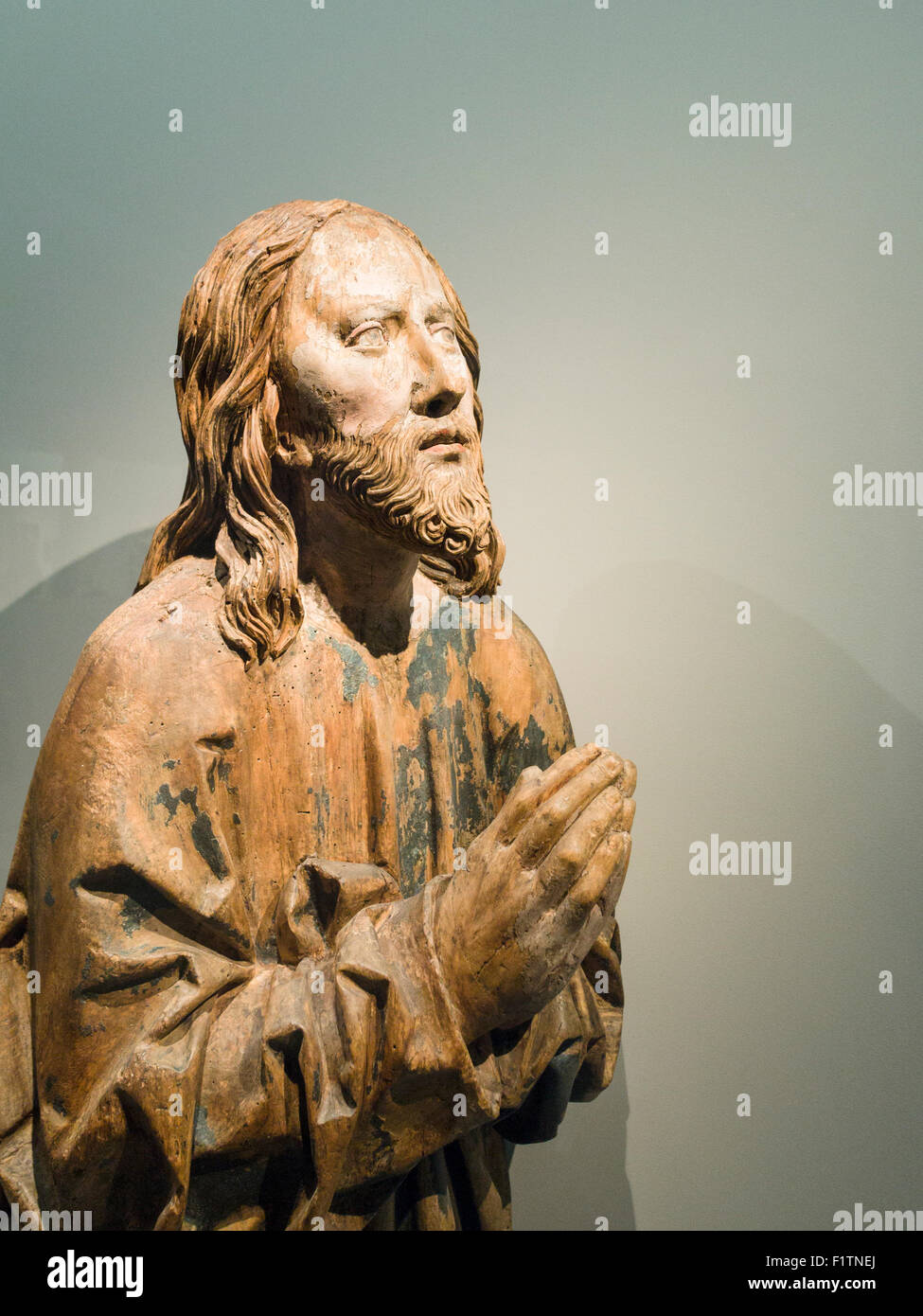 Medievale scultura in legno di Cristo pregando. Una statua usurata di un Cristo orante la figura, la sua vernice sfaldato per mostrare il legno Foto Stock