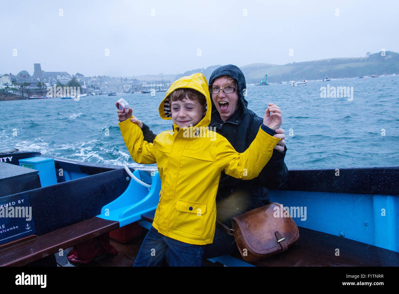 Madre e figlio (6 anni) sotto la pioggia sul traghetto Salcombe passeggeri tra East Portlemouth spiaggia e Salcombe, Devon, Inghilterra, Regno Unito. Foto Stock