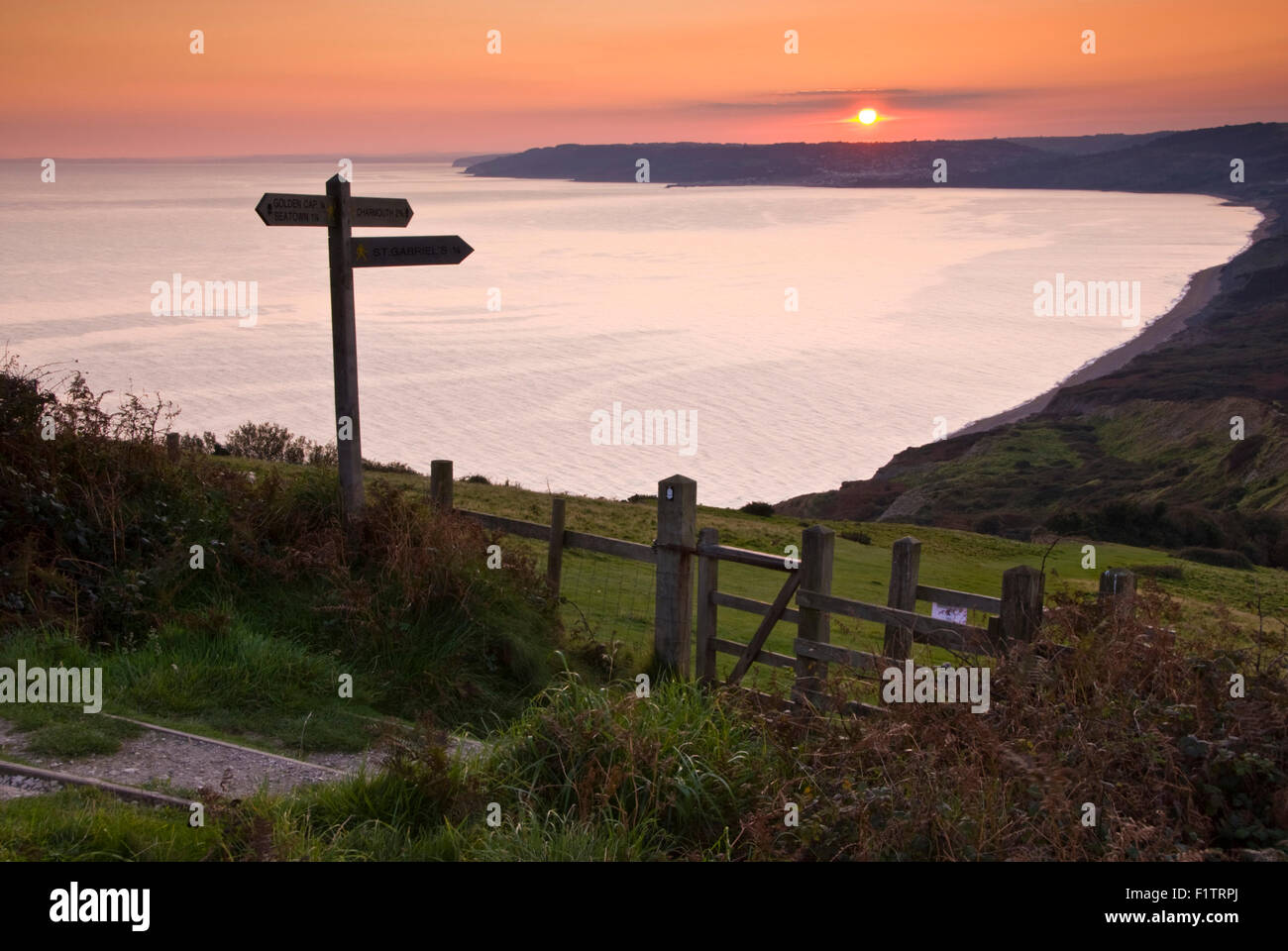 Il sole che tramonta sulla Lyme Regis, visto dalla costa sud-ovest il percorso sotto la cima del Golden Cap su Dorset la Jurassic Coast Foto Stock