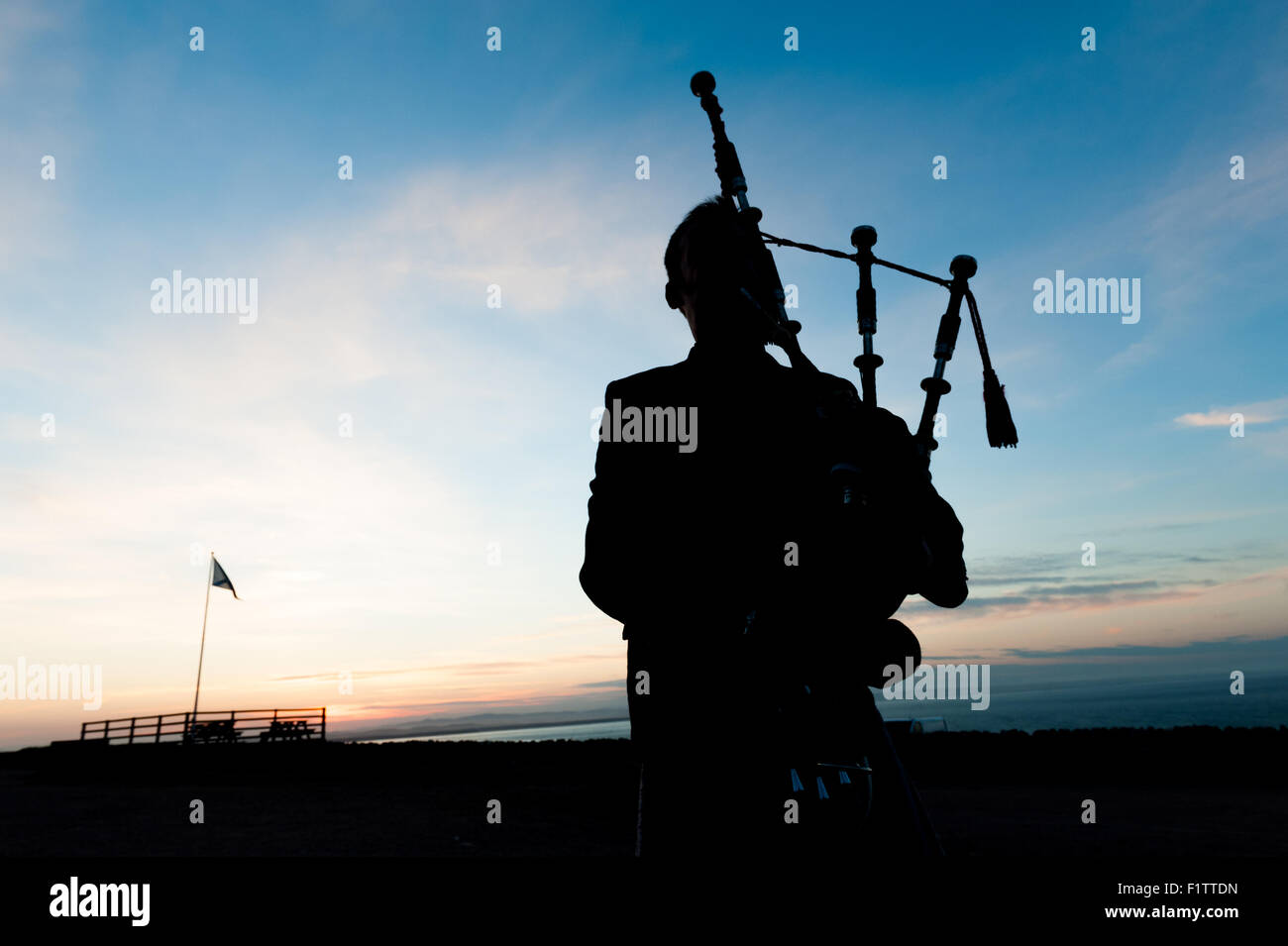 Silhouette di un irriconoscibile bagpiper su un paesaggio scozzese al tramonto Foto Stock