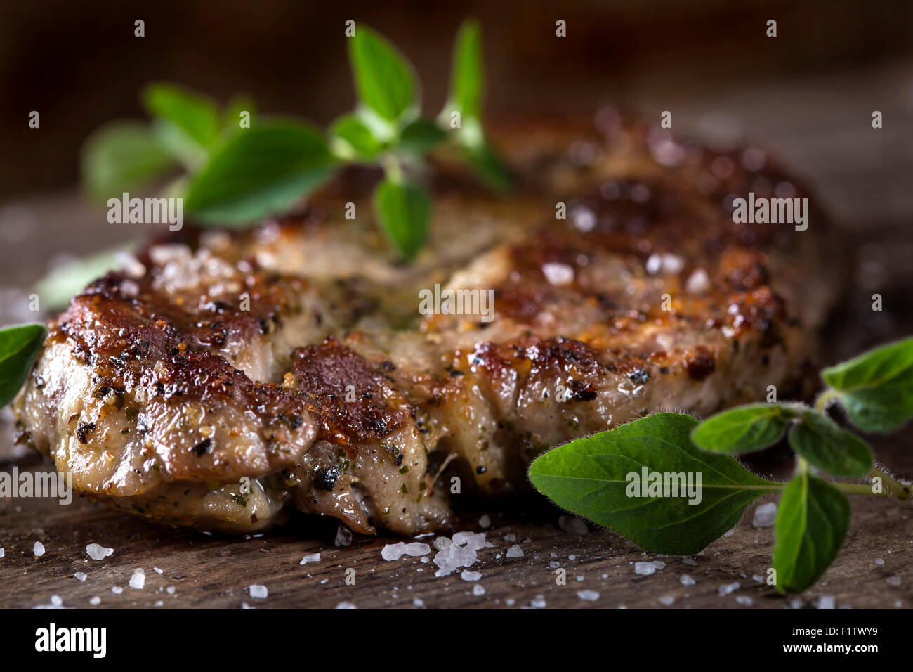 Pezzo di di grigliate di carne di maiale collo con erbe su un vecchio tavolo in legno Foto Stock