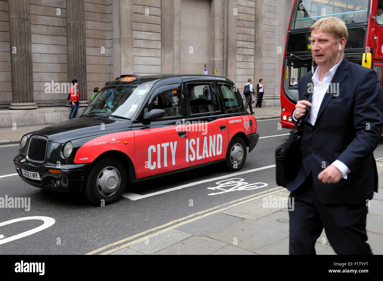 Imprenditore ascoltando l'ipod a piedi lungo Threadneedle Street con 'Città isola " segno su un taxi al di fuori della Banca d'Inghilterra a Londra REGNO UNITO KATHY DEWITT Foto Stock