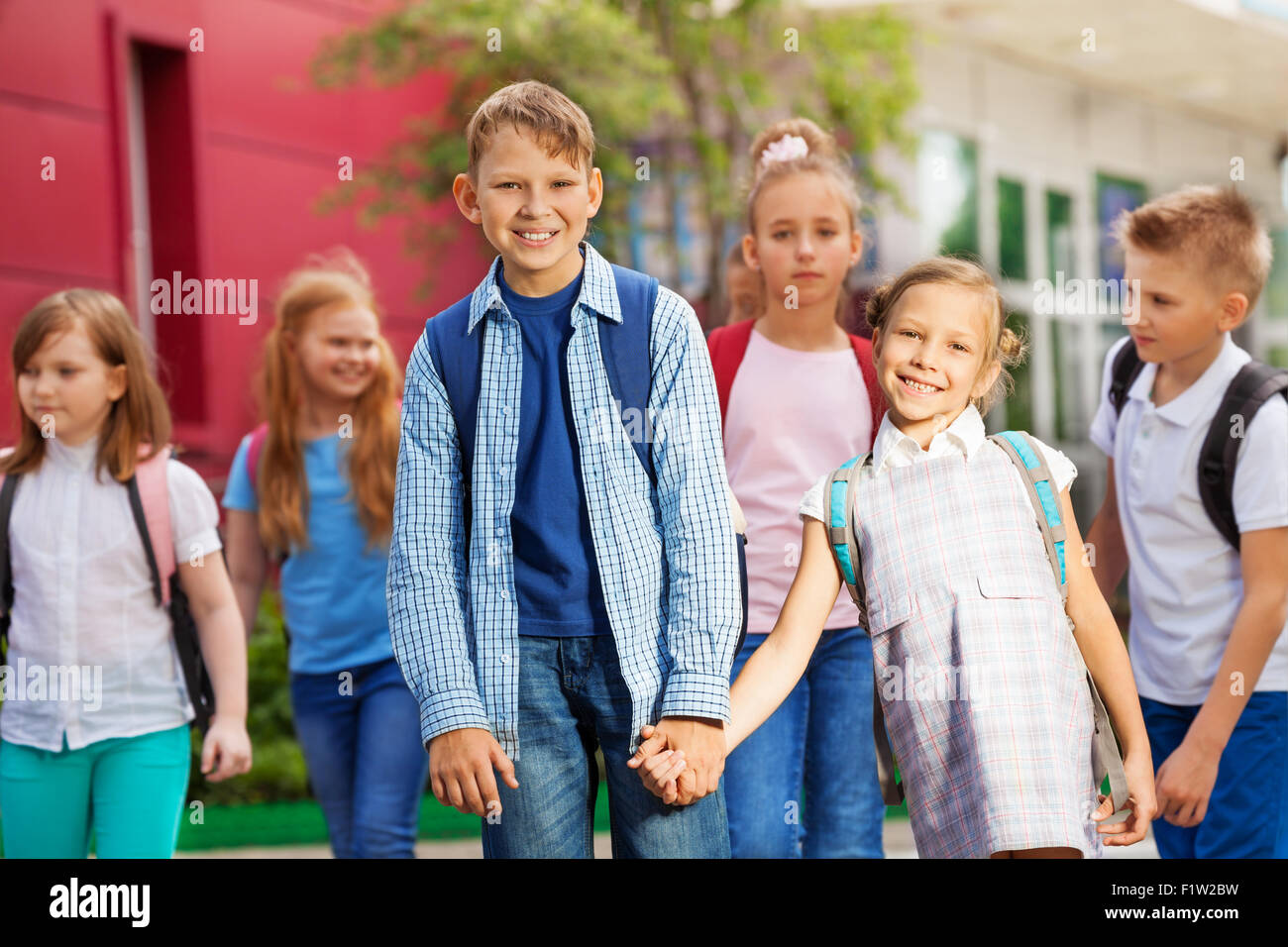 Un gruppo di ragazzi con zaini vicino edificio scolastico Foto Stock