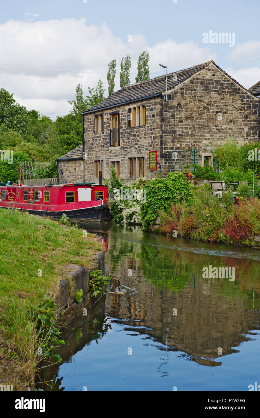 Tradizionale cottage in pietra con barca stretta davanti a Leeds e Liverpool canal, West Yorkshire, Regno Unito Foto Stock