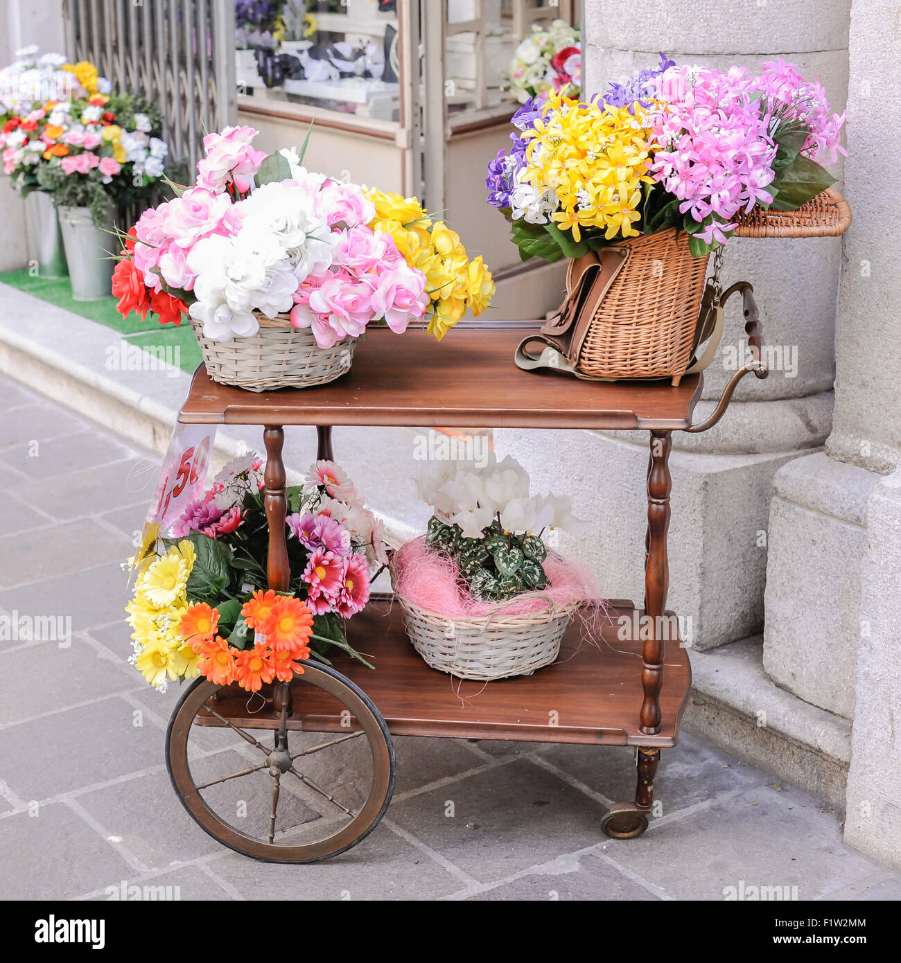 Un carrello con su cesti di vimini e un vecchio pesca in vimini cesto pieno di fiori per la vendita Foto Stock