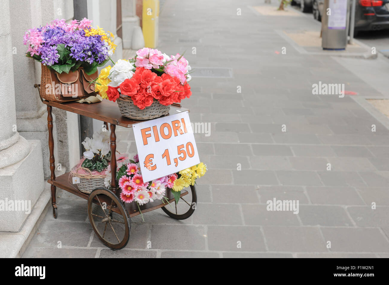 Un carrello con su cesti di vimini e un vecchio pesca in vimini cesto pieno di fiori per la vendita Foto Stock