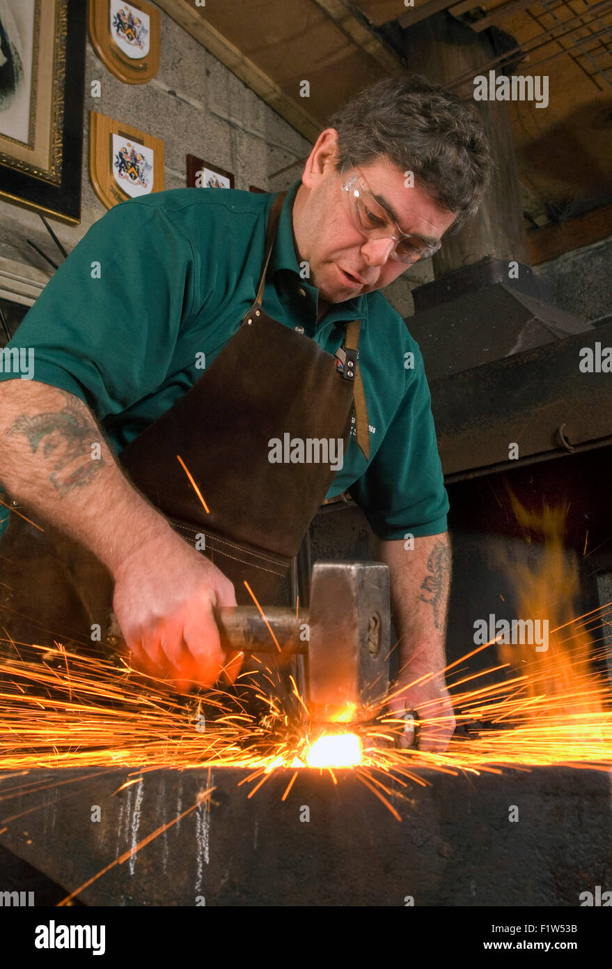 Fabbro Simon Grant-Jones martellare il metallo caldo con scintille battenti,nella sua fucina,dove egli è un artigiano metallurgo.Un REGNO UNITO Foto Stock