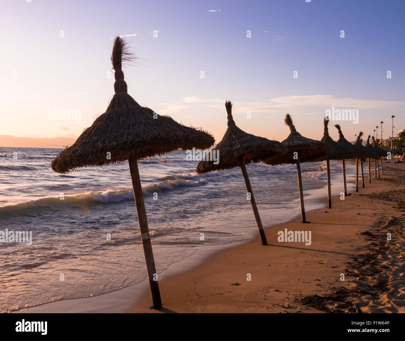 Palm ombrelloni sulla El Arenal Beach al tramonto, Maiorca, isole Baleari, Spagna Foto Stock
