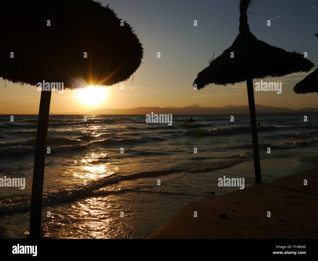 Palm ombrelloni sulla El Arenal Beach al tramonto, Maiorca, isole Baleari, Spagna Foto Stock