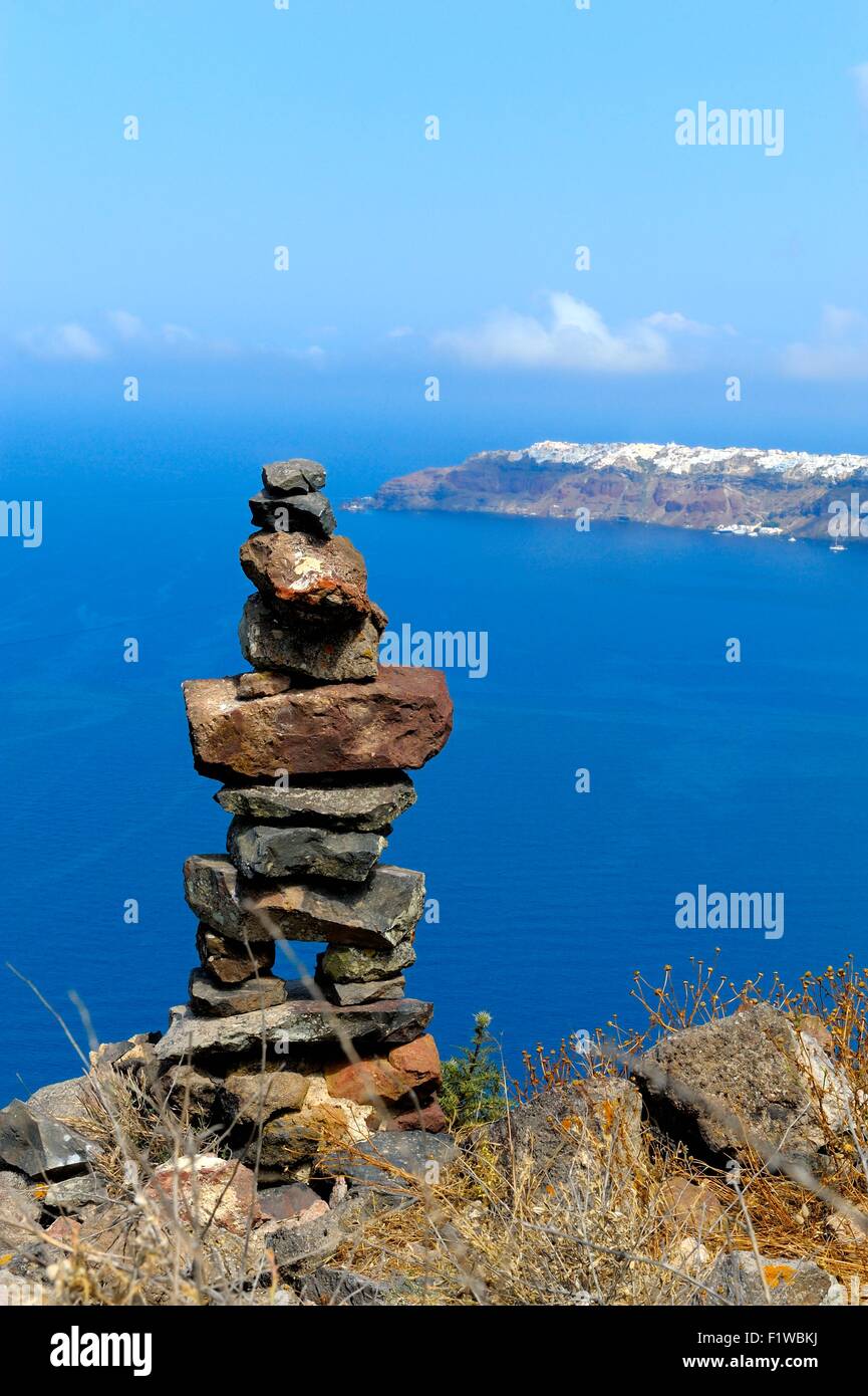 Un mucchio di pietre impilate sul bordo della caldera con il villaggio di Oia in lontananza Santorini, Grecia Foto Stock