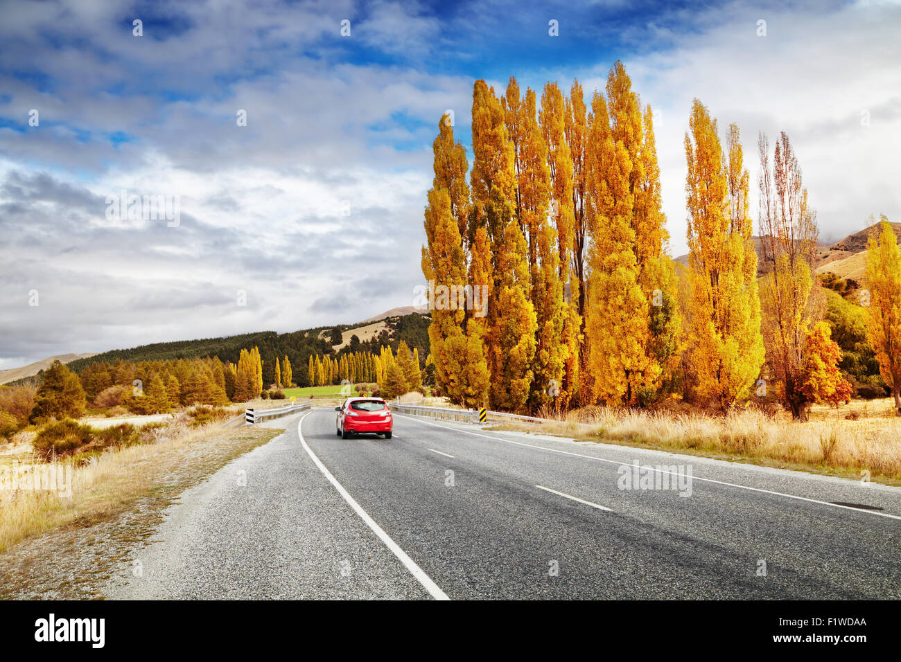 Paesaggio autunnale con strada e auto rossa, Nuova Zelanda Foto Stock