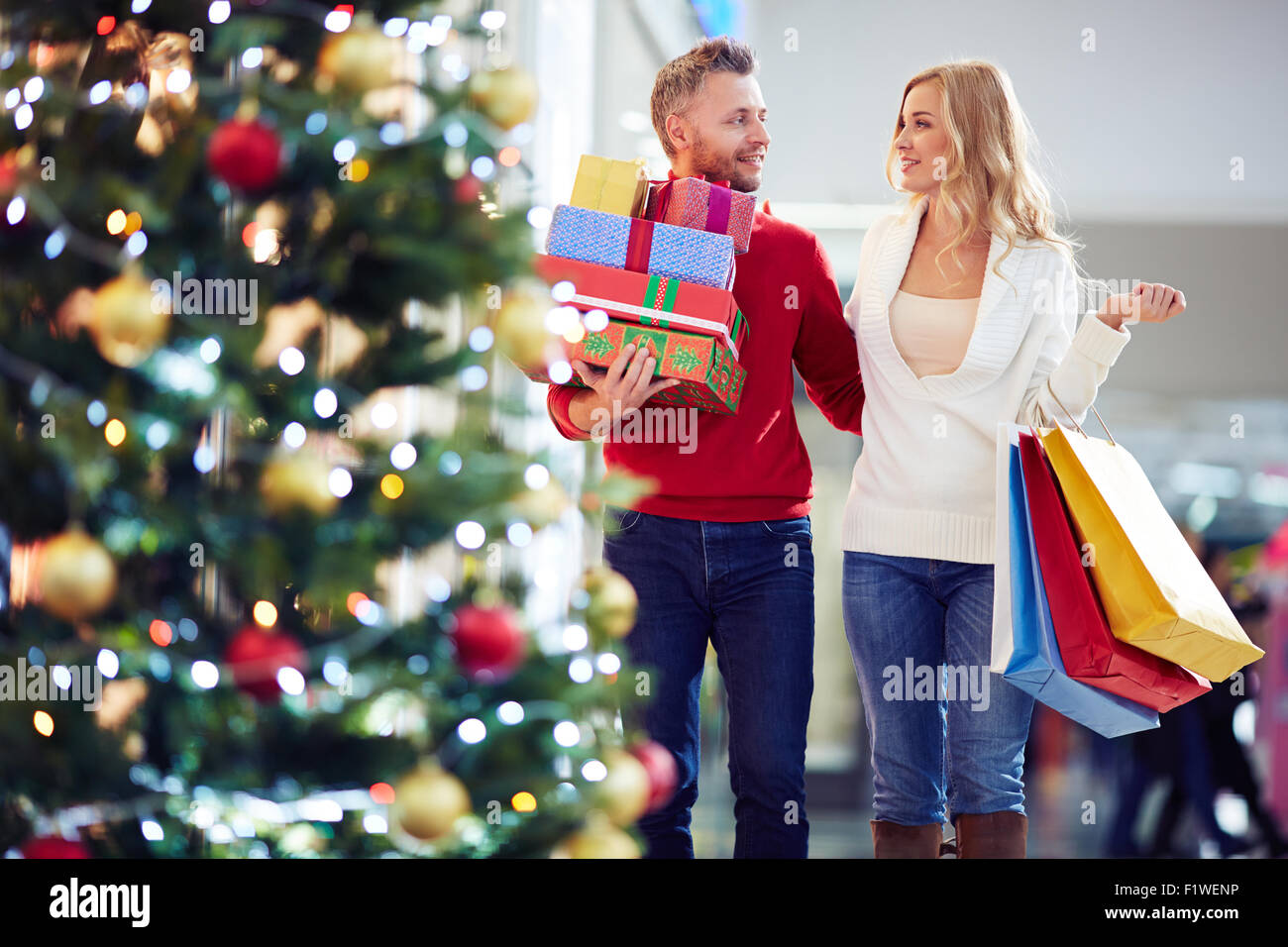 Affettuosa giovane portando regali di Natale mentre lo shopping nel centro commerciale Foto Stock