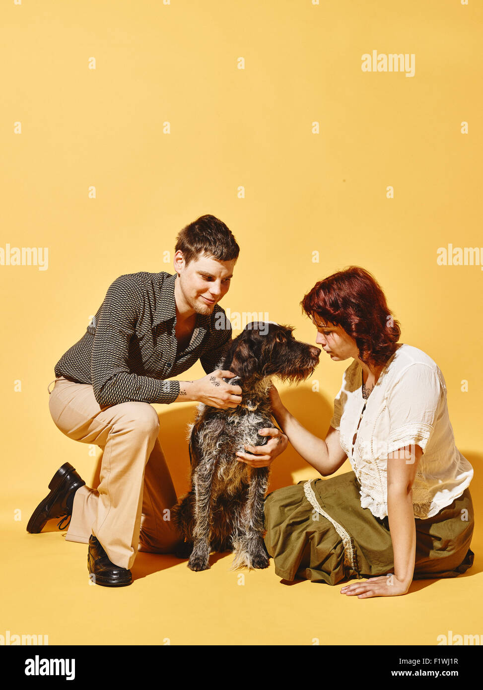 Giovane e cane insieme, 70's guardare tema, sfondo giallo Foto Stock