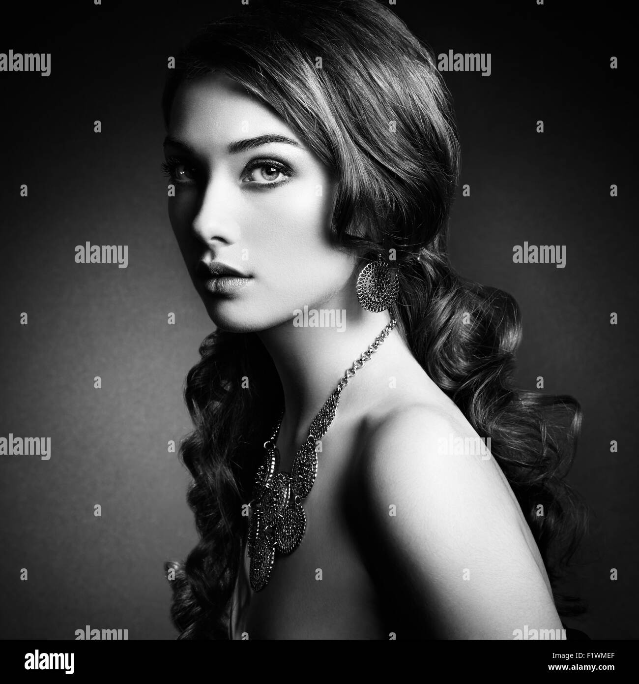 La bellezza della donna con lunghi capelli ricci. Bellissima ragazza con eleganti acconciature. Foto di moda. In bianco e nero Foto Stock