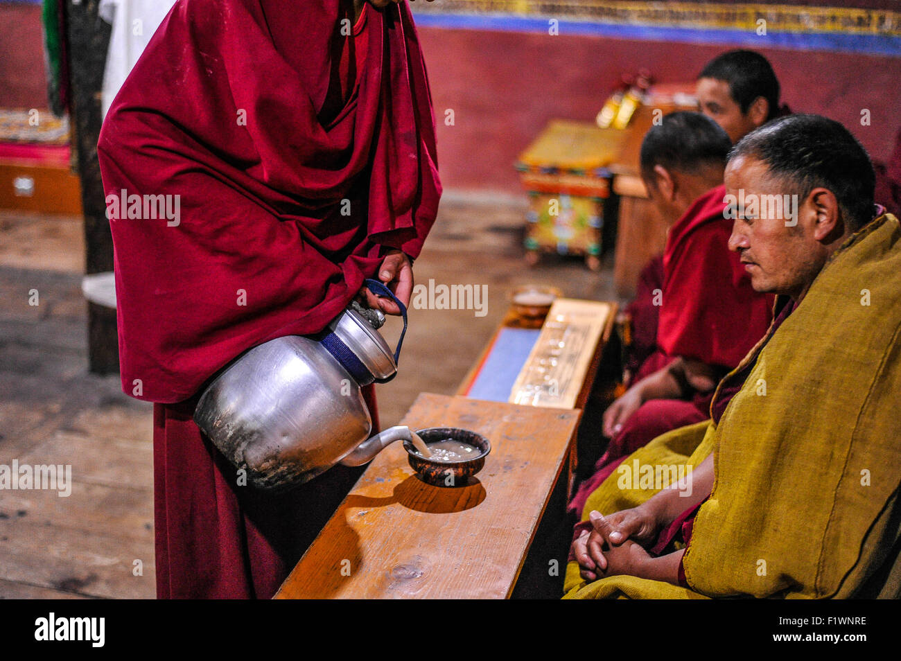 India Jammu Kashmir Ladakh Thiksay Monastero un monaco versando il tè durante le preghiere del mattino Foto Stock