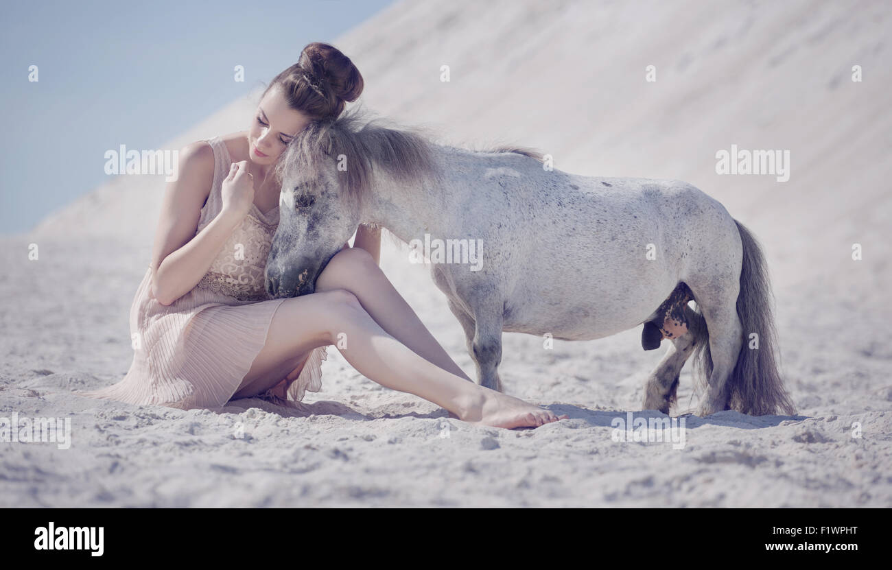 Piuttosto giovane donna abbracciando il cavallino bianco Foto Stock