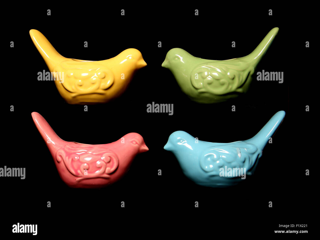 Quattro coloratissimi uccelli ornamenti di forma su sfondo nero Foto Stock