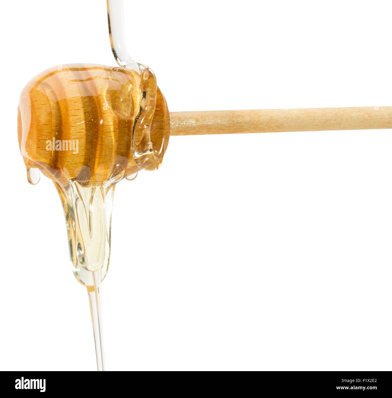 Il miele il gocciolamento da un cucchiaio di legno su sfondo bianco. Foto Stock