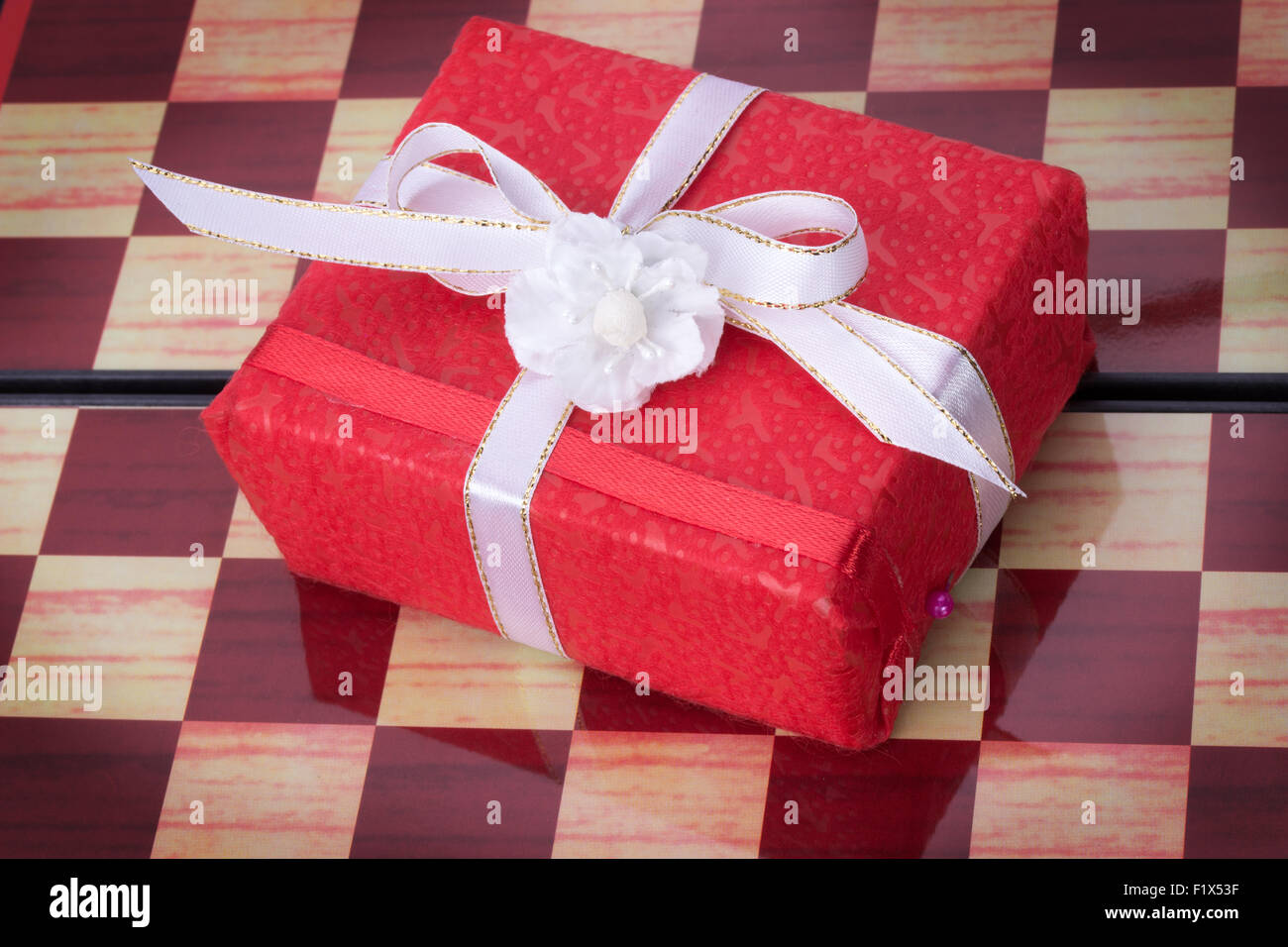 Confezione regalo rossa su una scacchiera. Foto Stock