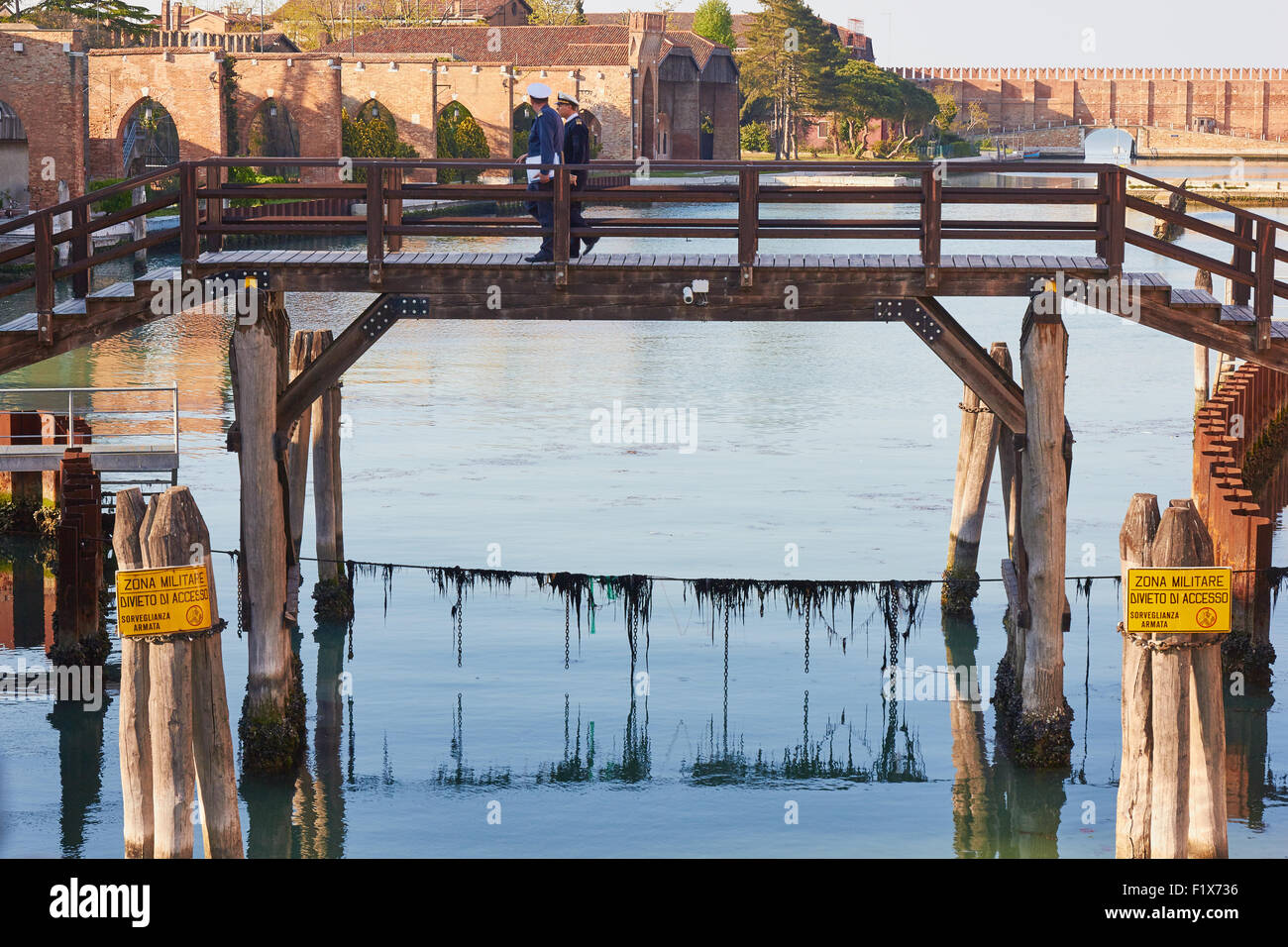 Due ufficiali navali attraversando un ponte in Arsenale un complesso di ex cantieri e armory a Venezia Veneto Italia Europa Foto Stock