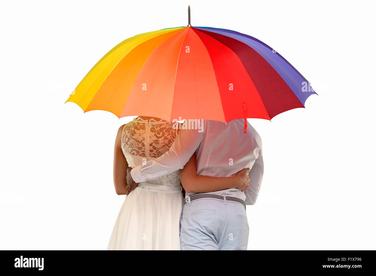 Tre quarti di vista posteriore di una coppia romantica sotto un ombrello coloratissimo, isolato su bianco Foto Stock