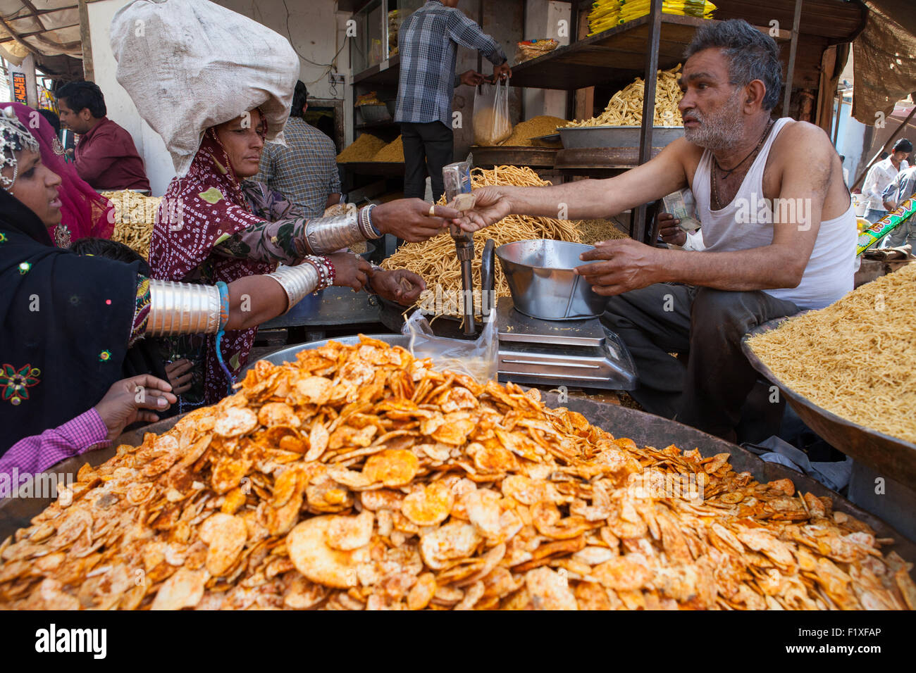 Venditore a vendere namkeen e chat per donne tribali nel mercato a Bikaner Foto Stock