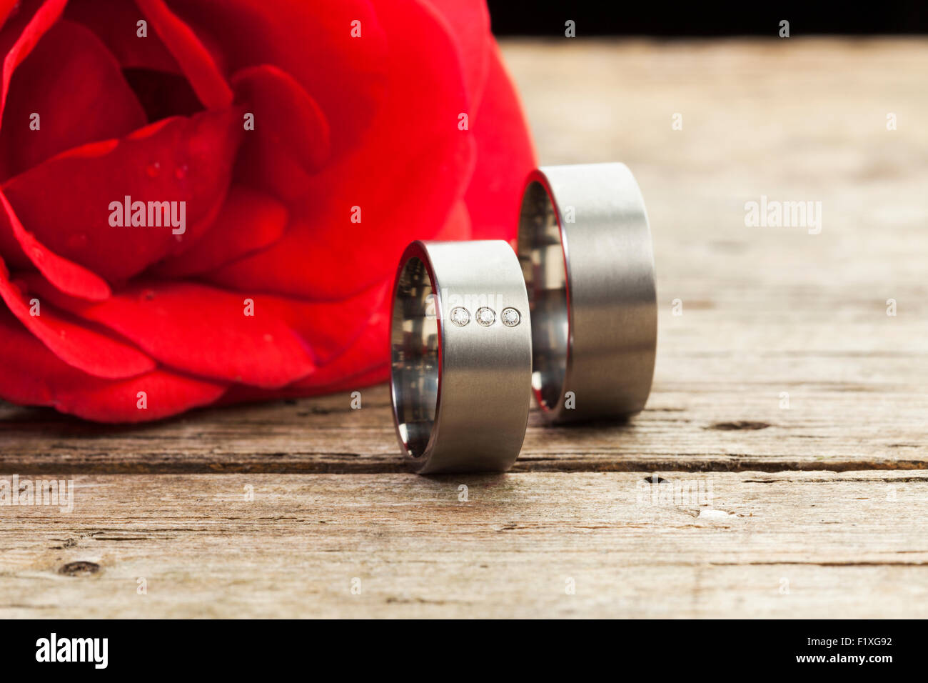 Argento o platino fedi sul tavolo di legno, Red Rose in background Foto Stock
