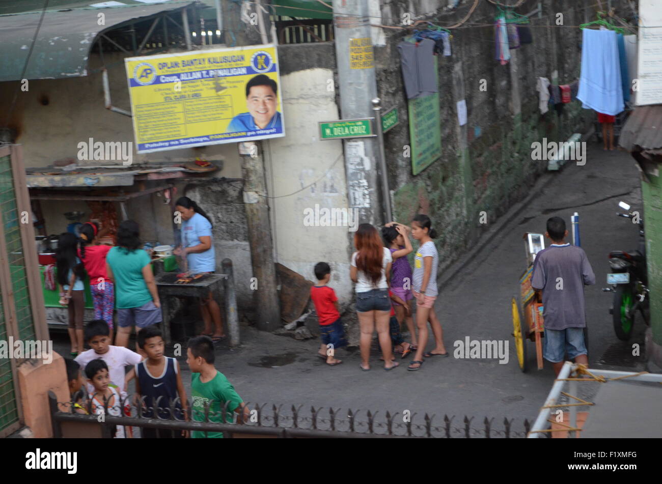 M.Dela Cruz, Manila.A streetcorner wherecrowds riuniscono thesausages totaste che sono scaldati su them.above thematthe politico locale Foto Stock