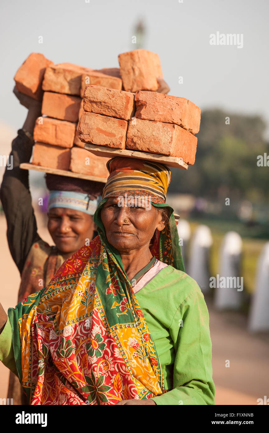 Delhi, India. Due donne operai che trasportano mattoni sulle loro teste. Foto Stock