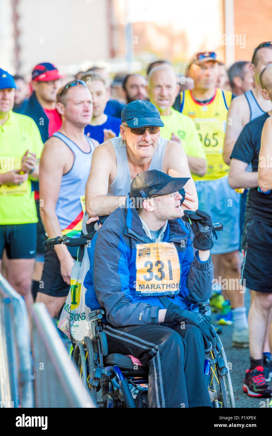 Un uomo in sedia a rotelle essendo spinto in tutto il corso dell'intagliatori sponsorizzato la maratona di Wolverhampton Regno Unito Foto Stock