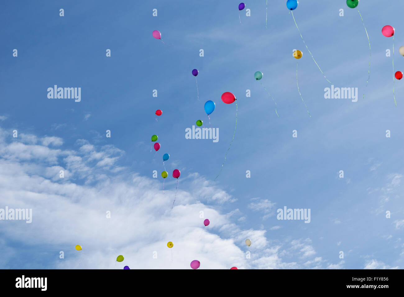 Molti di palloncini colorati volare (hover) nel cielo blu con nuvole Foto Stock