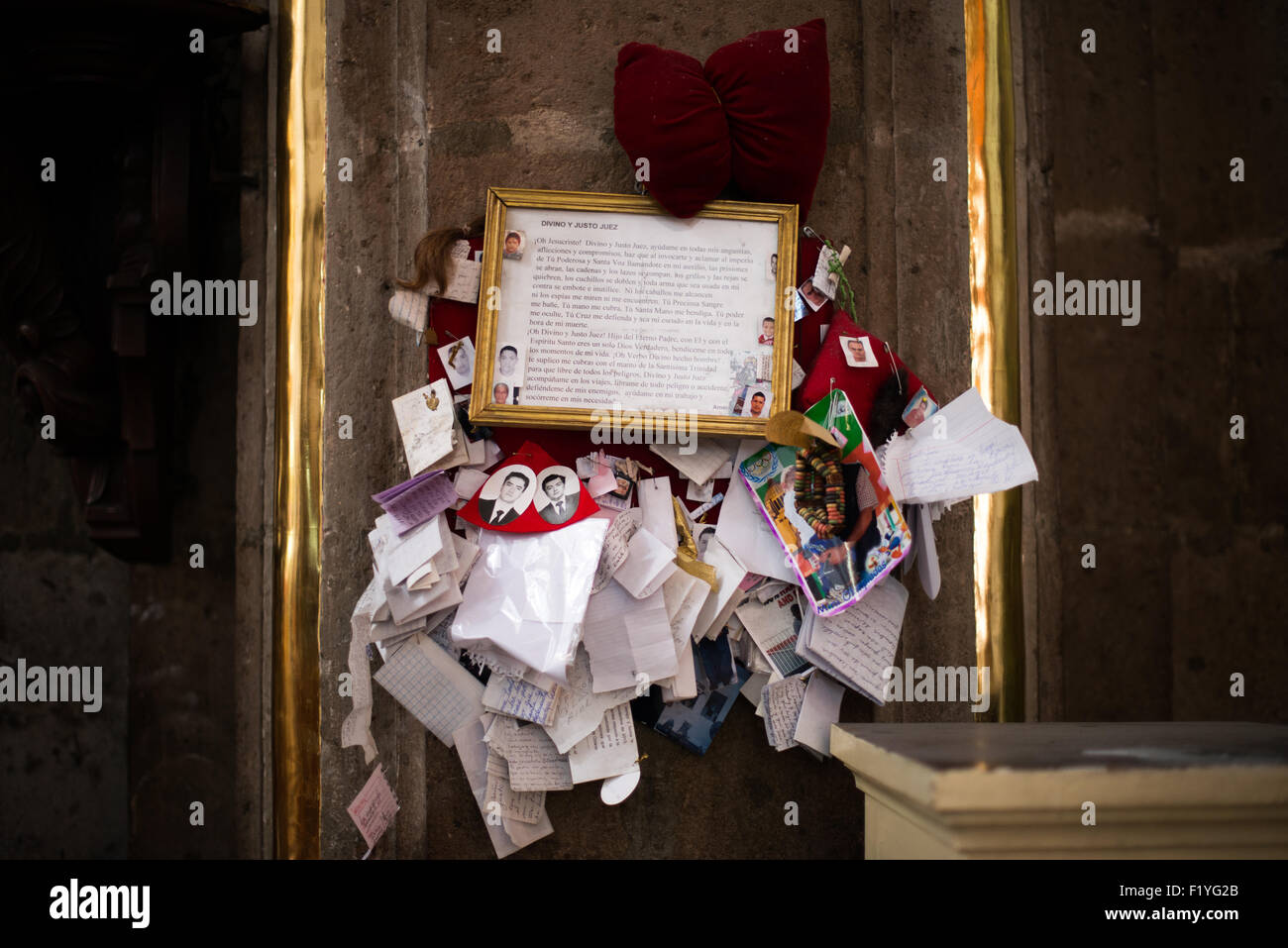 Iglesia de San Bernardo Folk Shrine città del Messico // CITTÀ DEL MESSICO, Messico - Un testo di preghiera incorniciato circondato da fotografie devozionali, note e souvenir crea un santuario popolare all'interno dell'Iglesia de San Bernardo. L'esposizione mostra le continue tradizioni religiose di questa chiesa del XVII secolo fondata nel 1636 come parte del Convento del Dulcísimo Nombre de María del Glorioso San Bernardo. La preghiera al Divino e giudice giusto rappresenta le pratiche devozionali cattoliche popolari comuni nella cultura religiosa messicana. Le offerte personali e i ricordi che circondano il testo riflettono la comunità attiva Foto Stock