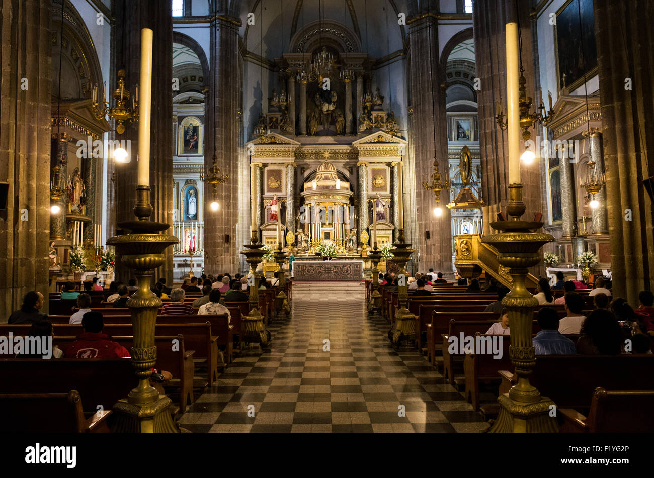 La Profesa Church Altar città del Messico // CITTÀ DEL MESSICO, Messico — la navata principale del Tempio di San Felipe Neri conduce verso l'altare ornato della chiesa nel quartiere Centro Histórico di città del Messico. Spesso conosciuta semplicemente come la Profesa, questa chiesa cattolica romana del XVII secolo fu fondata dai gesuiti ed è stata il luogo di numerosi eventi significativi nella storia messicana. Il tempio si trova nel cuore dell'area del centro di città del Messico, riconosciuta patrimonio dell'umanità dall'UNESCO. Il nome formale della chiesa riflette la sua dedica a San Filippo Neri, il sacerdote italiano del XVI secolo che fu Foto Stock