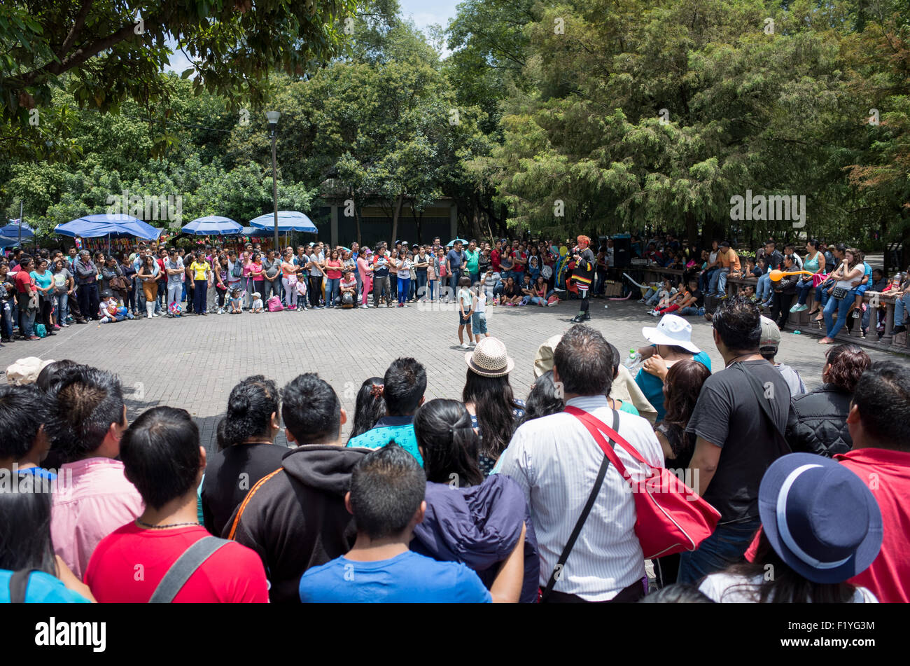 Città del Messico - una strada attore coinvolge due piccole bambine nel suo agire e attira un folto pubblico in basco de Chapultepec, un grande e famoso parco pubblico nel centro di Città del Messico. Foto Stock