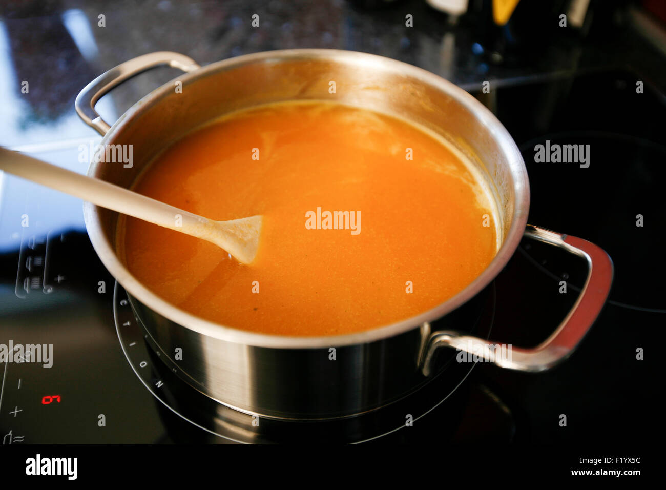 La zuppa in pentola con il cucchiaio di legno Foto Stock