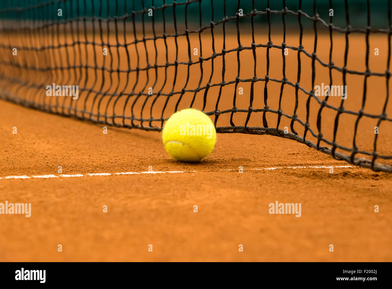 Giallo palla da tennis su una argilla rossa corte Foto Stock
