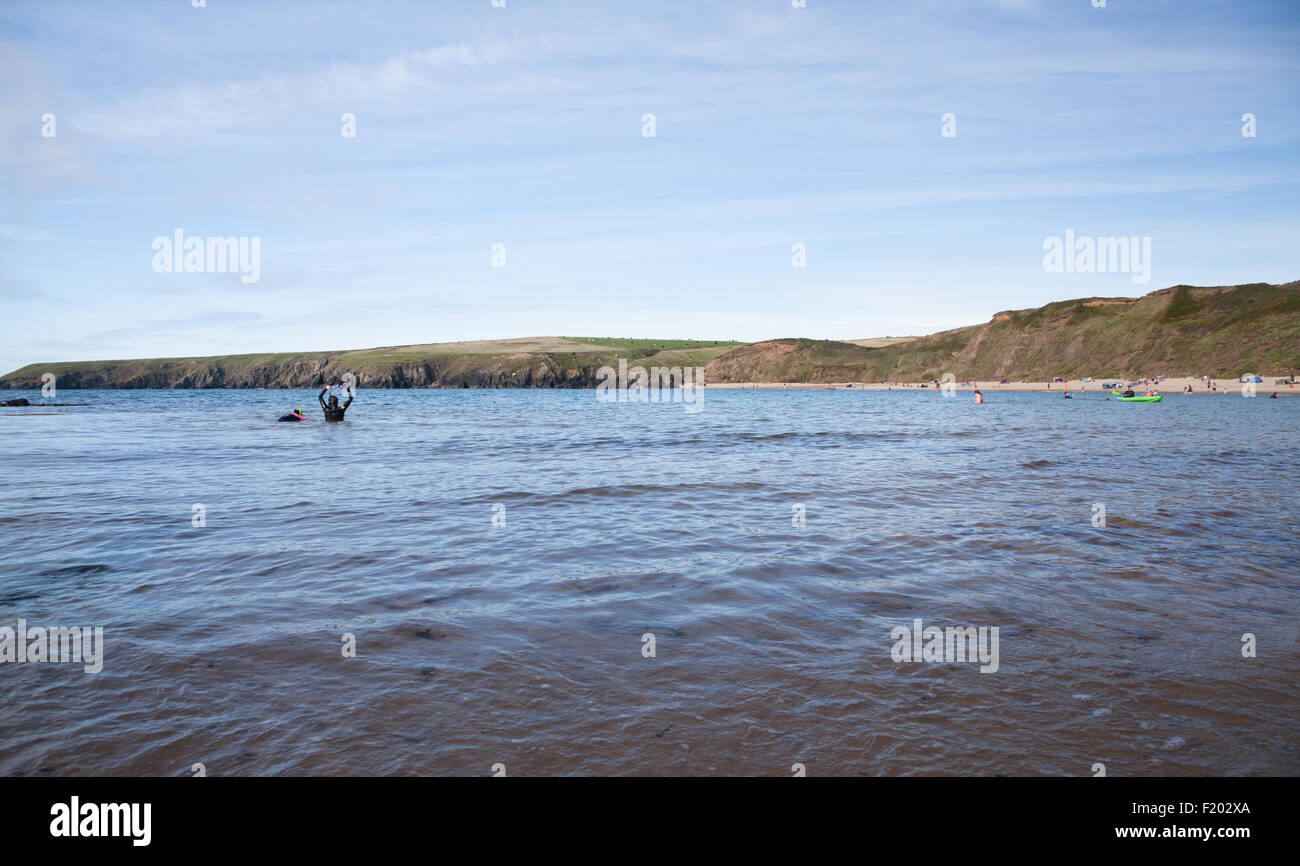 Due donne che indossano vestiti bagnati e boccagli in acqua in un sibilo Sands / Porth Oer, Aberdaron, Llyn Peninsula in estate Foto Stock