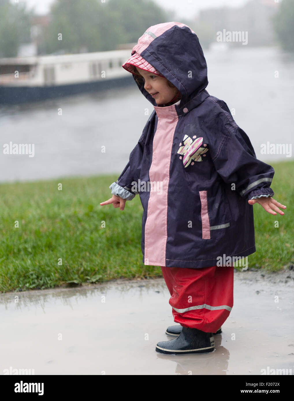 Kleinkind steht bei Regen in einer Pfütze Foto Stock