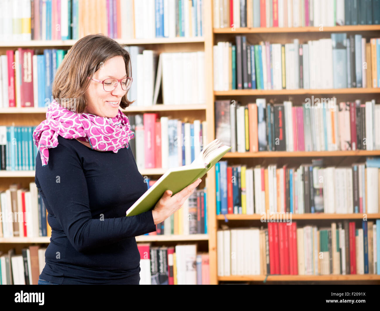 Frau liest Buch in Bibliothek Foto Stock