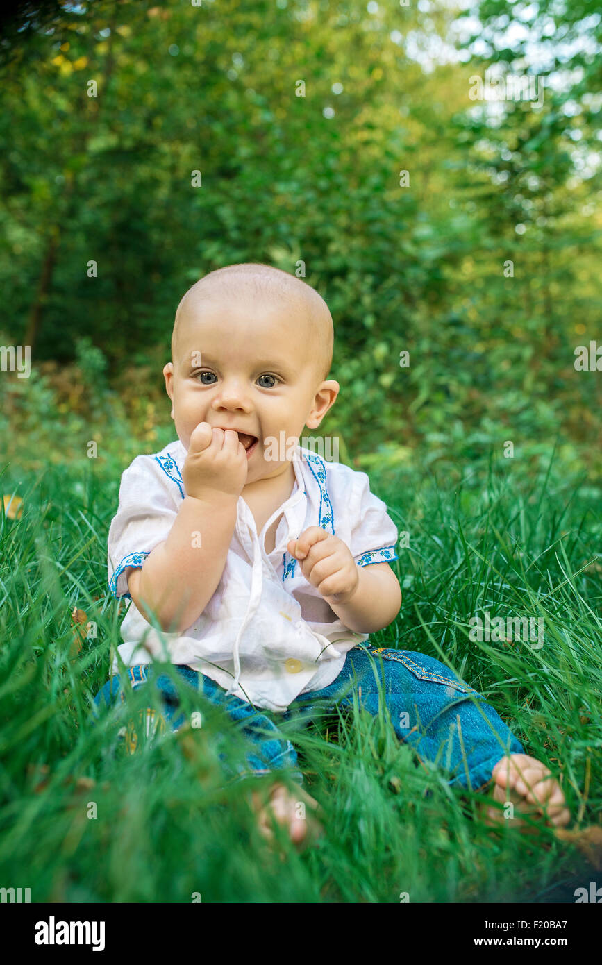 Felice, sorridente baby sull'erba verde nel parco Foto Stock