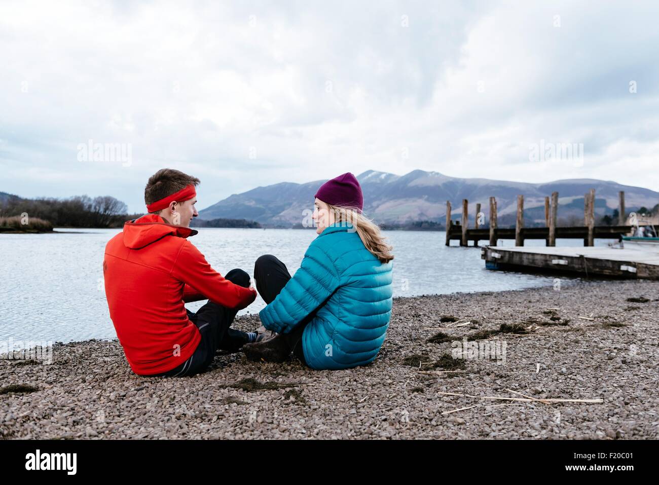 Coppia giovane escursionismo, seduta da Waters Edge, Derwent Water, Keswick, Lake District, Cumbria, Regno Unito Foto Stock