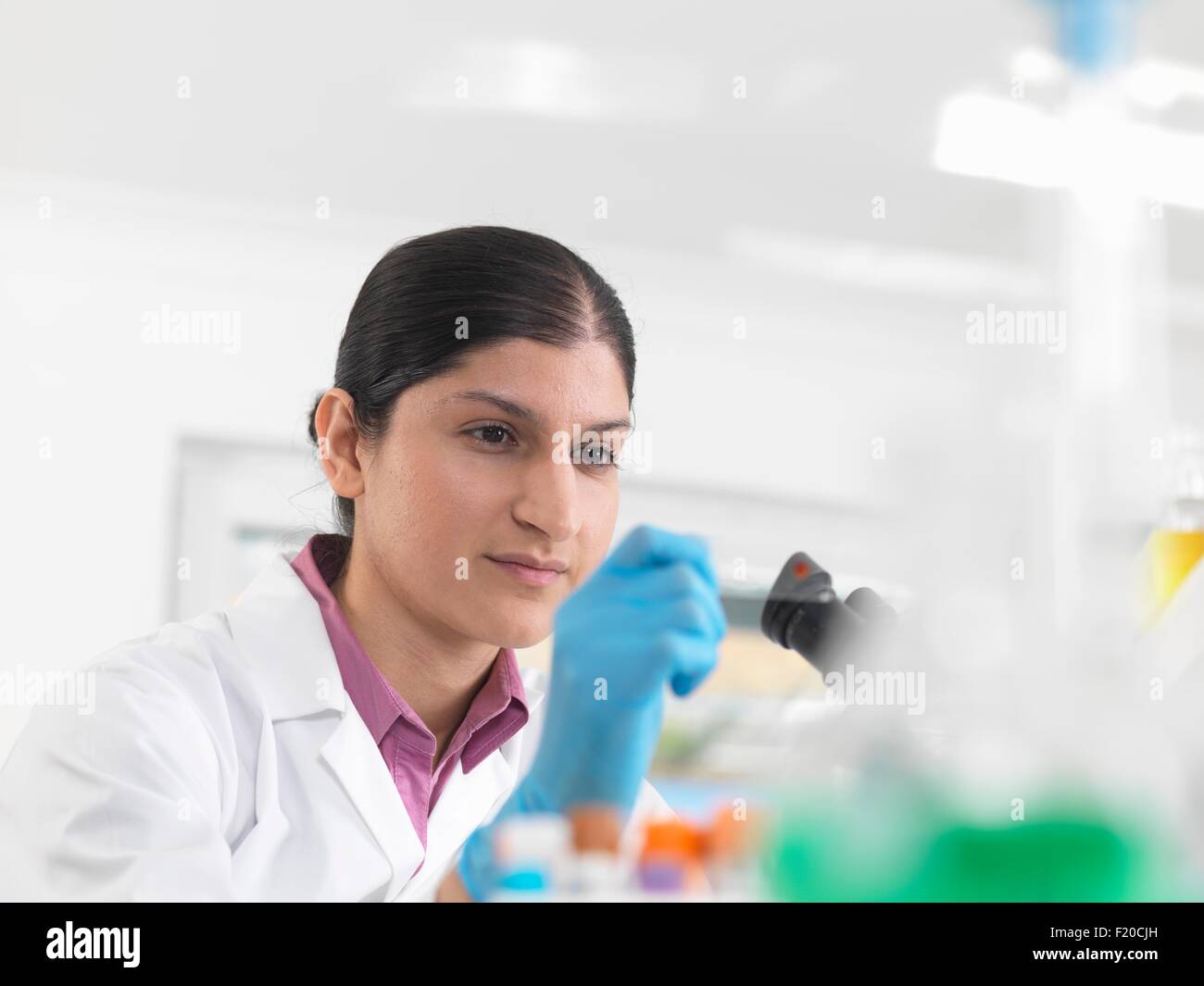 Giovane donna scienziato sangue visualizzazione diapositiva durante la sperimentazione clinica di medico di campioni in laboratorio Foto Stock