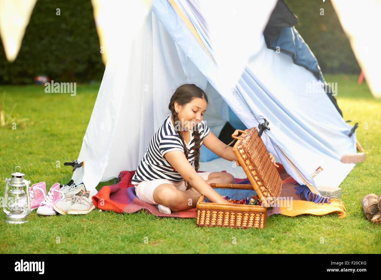 La ragazza lo svuotamento cestino da picnic nella parte anteriore della tenda casalinghi in giardino Foto Stock