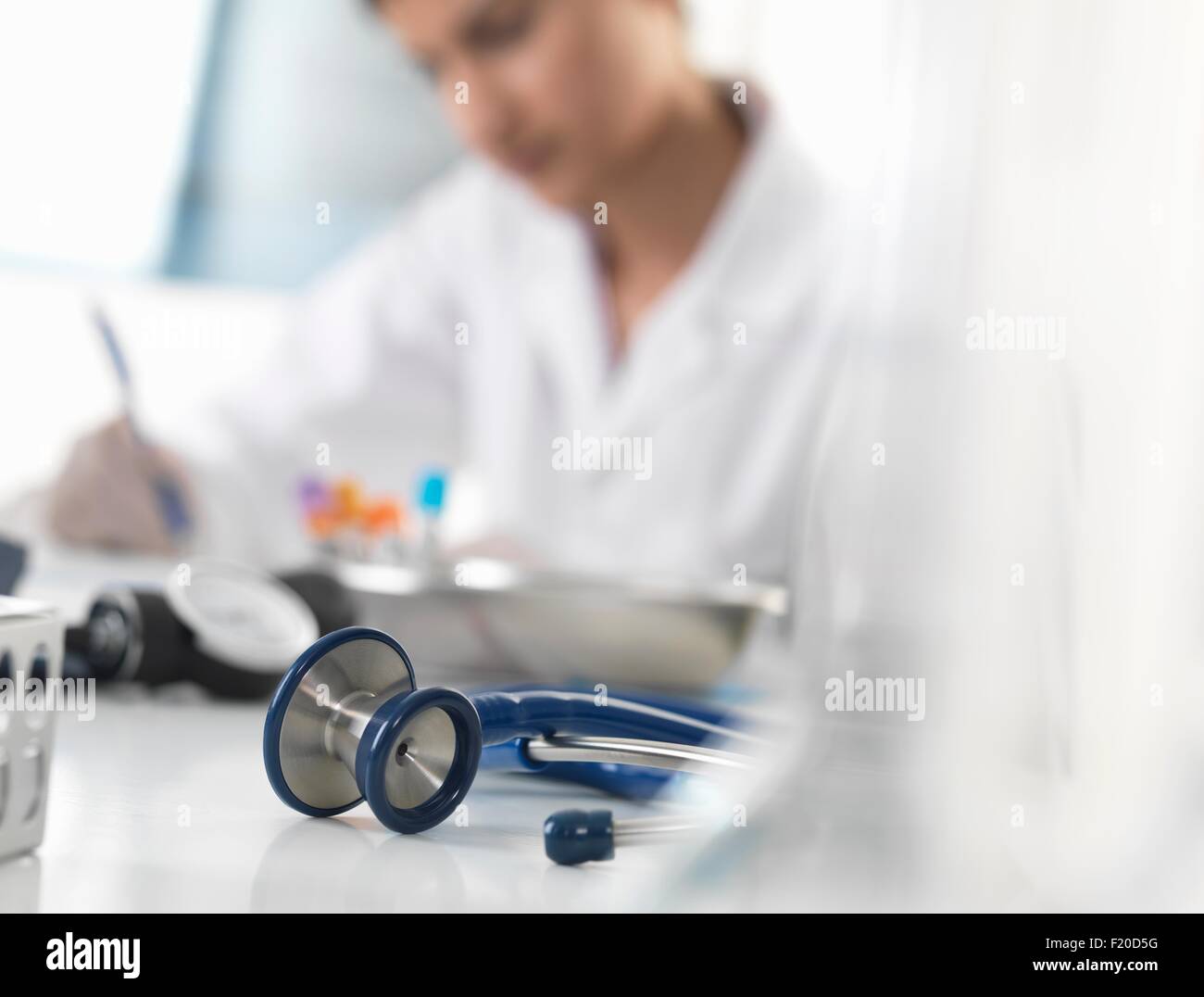 Medico donna scrivendo documentazione medica alla scrivania in clinica Foto Stock