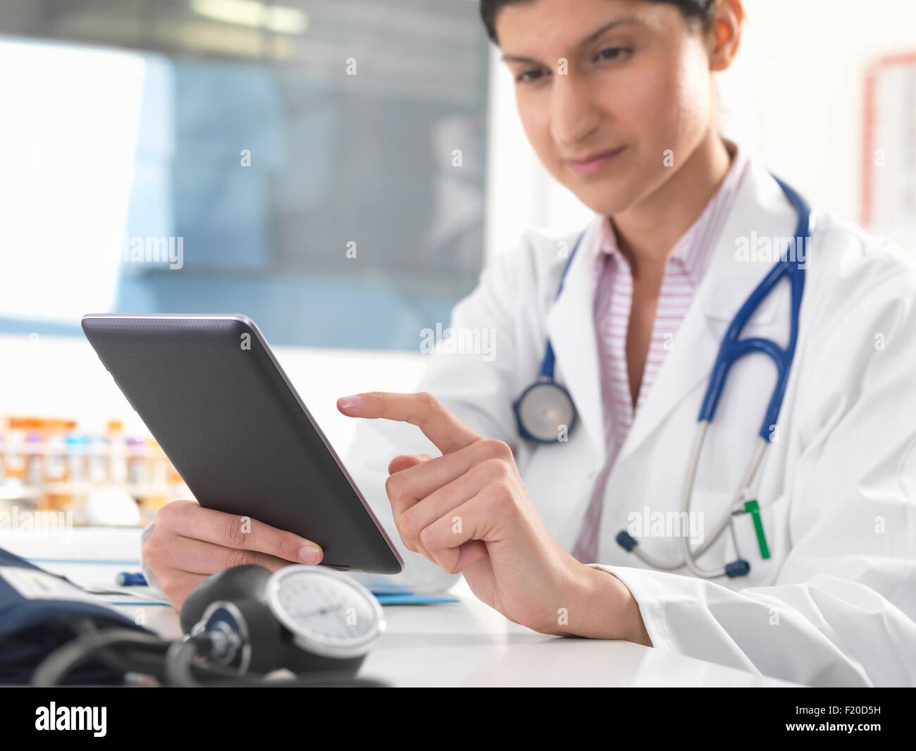 Medico donna aggiornamento record medico sulla tavoletta digitale Foto Stock